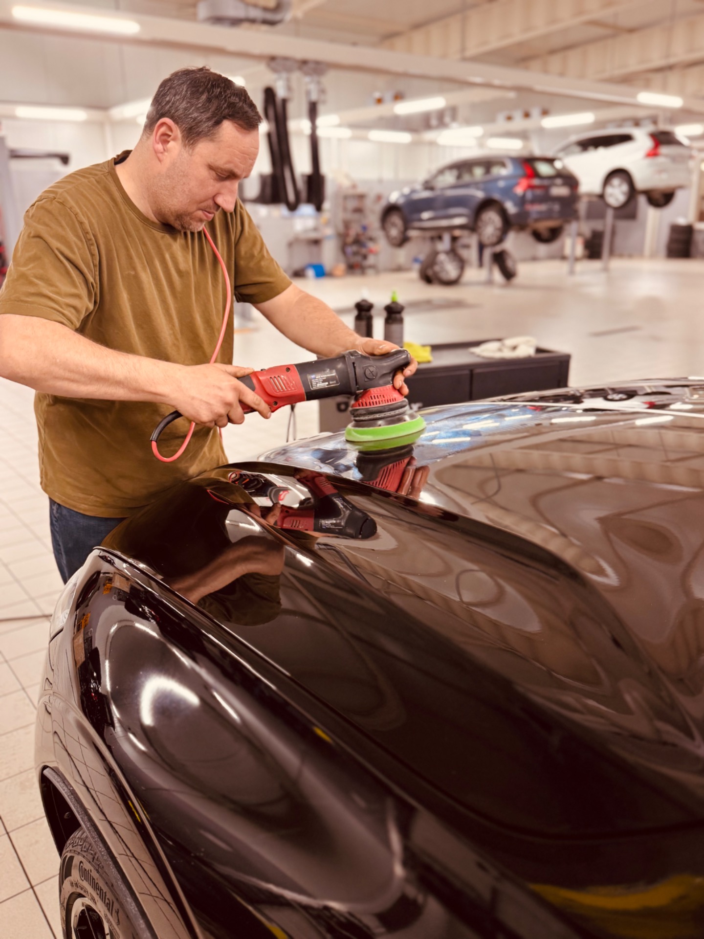 Detailer van Luxury Shine polijst een donkere wagen met een professionele polijstmachine.